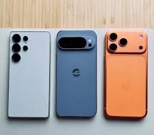 Latest flagship smartphones comparison showing iPhone 17 Pro Max, Samsung Galaxy S25 Ultra, and Google Pixel 10 Pro placed side by side on a wooden surface